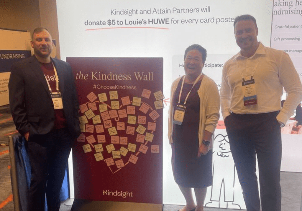 Kindsight employees standing beside Kindness wall
